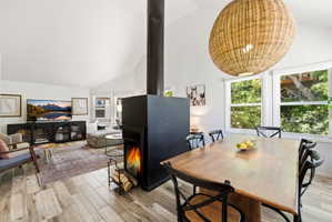 Vaulted ceilings and wood-finish flooring define this open-concept space, featuring a modern freestanding fireplace