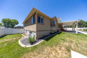 Two-story residence featuring stucco siding, a covered carport, and a white vinyl fence enclosing a portion of the yard