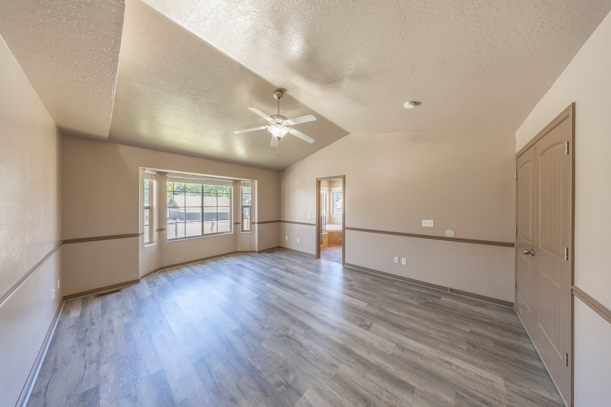 Spacious room featuring vaulted ceilings, a ceiling fan, and wood-finish flooring