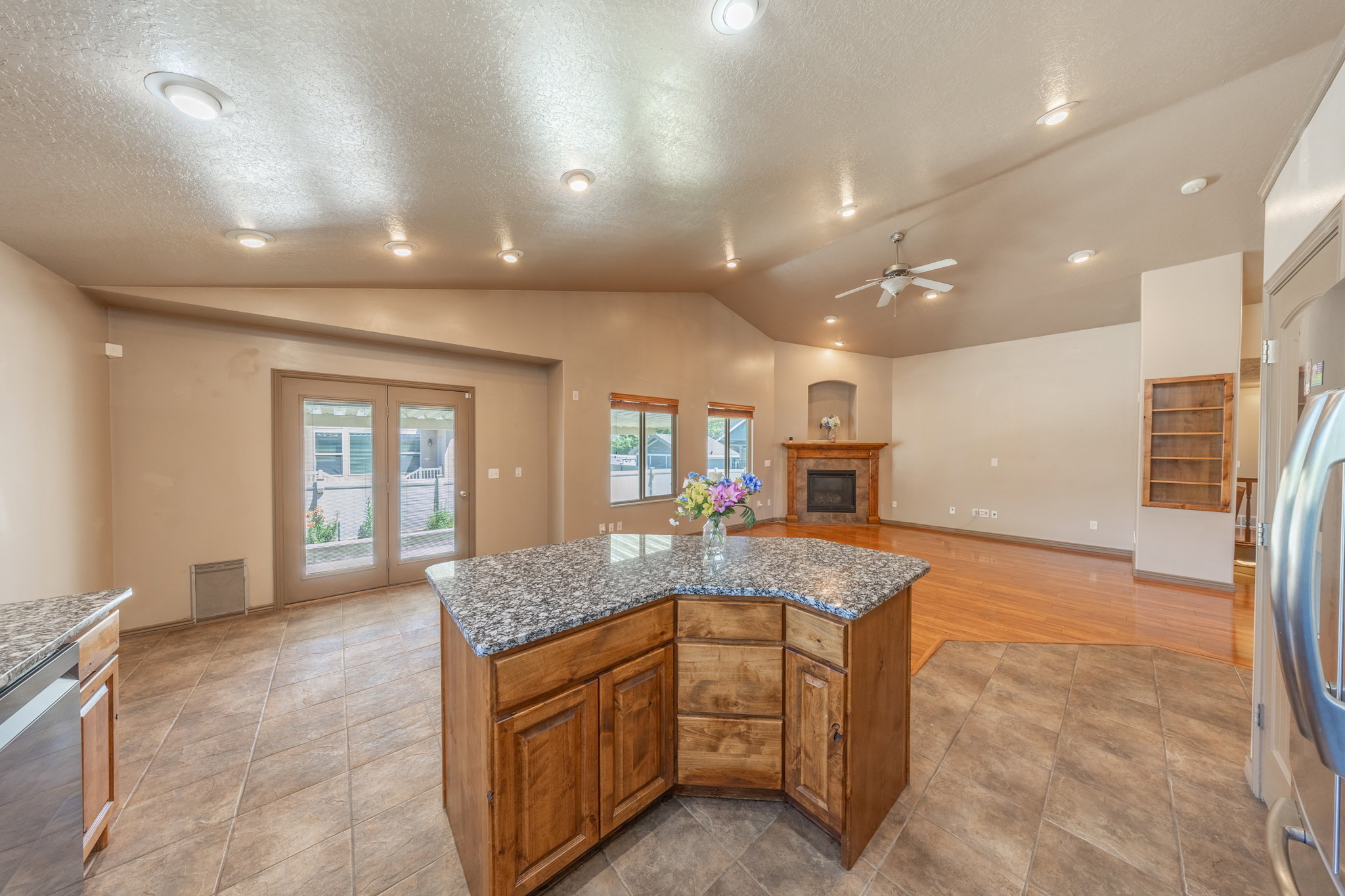 Open-concept living area featuring a central island with a stone-finish countertop, recessed lighting, and a ceiling fan