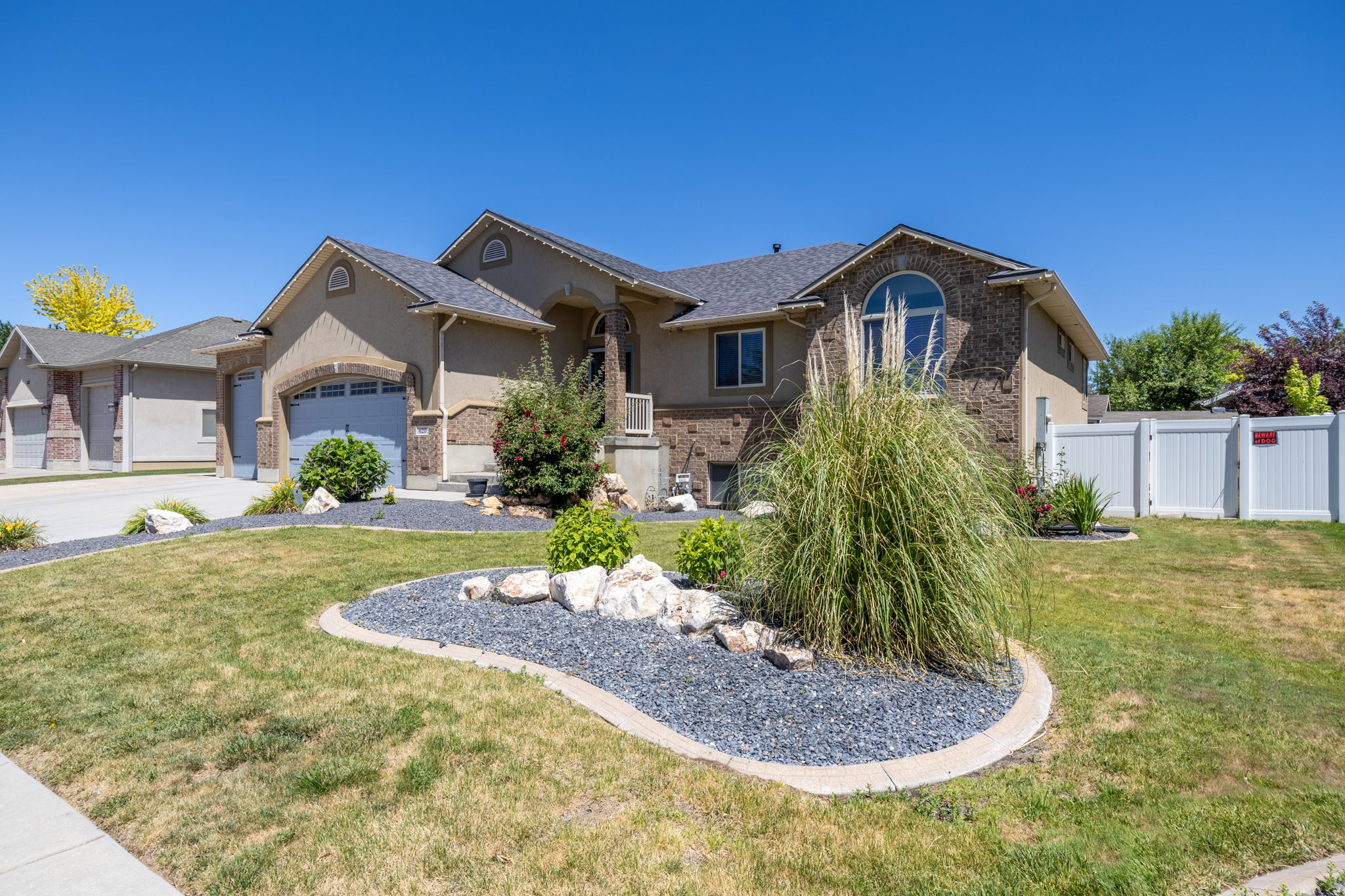 Tan exterior with stone accents and a gray shingle roof