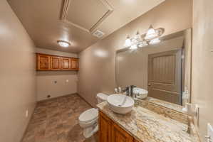 Vanity area featuring a vessel sink, stone countertop, wood-finish cabinetry, and a large wall-mounted mirror with a four-light fixture