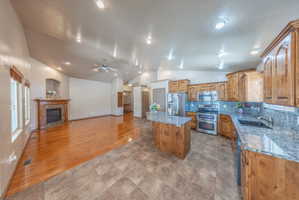Open concept living space featuring a kitchen with wood cabinetry, granite countertops, and stainless steel appliances