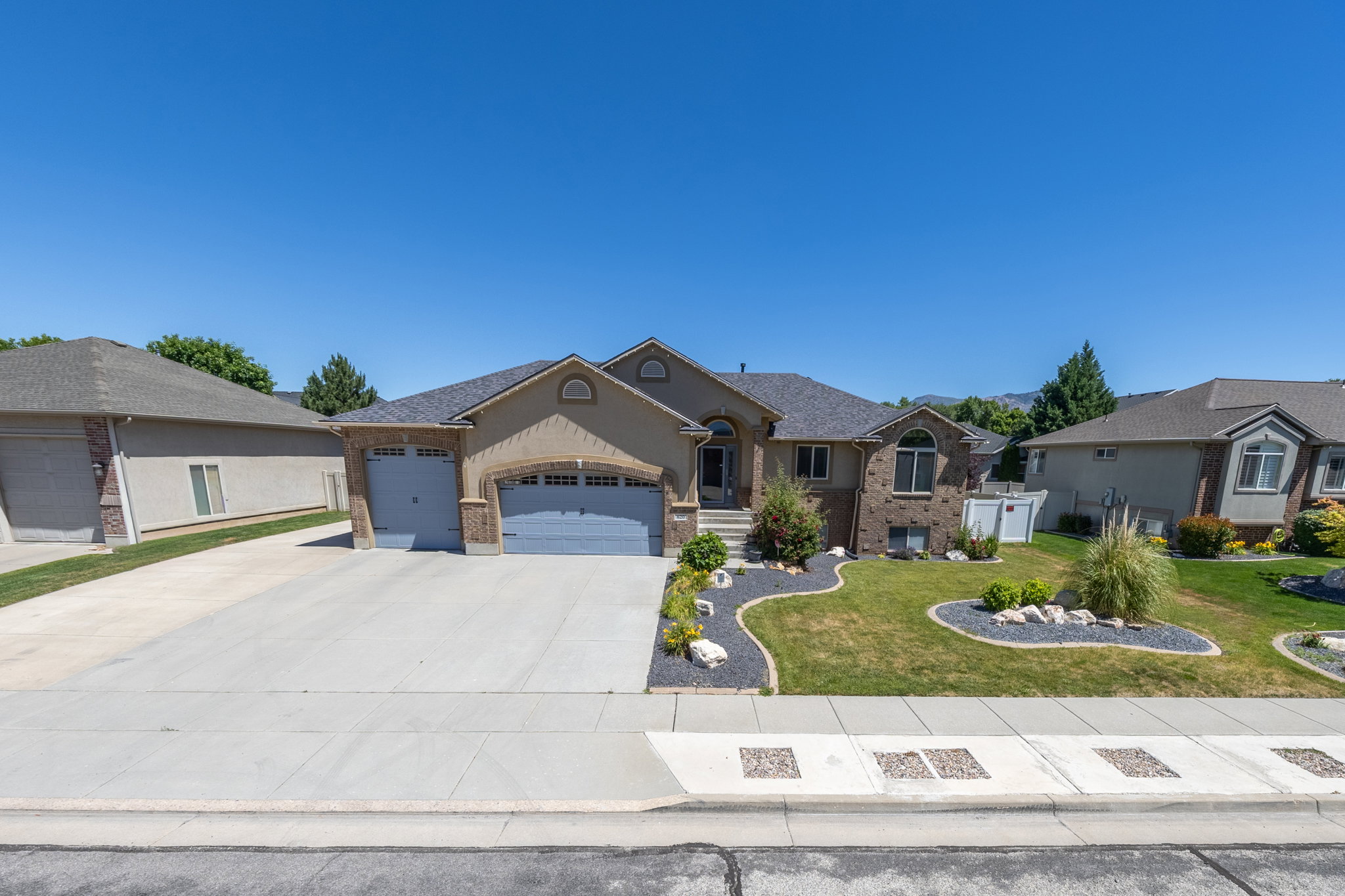 Stucco and brick exterior residence with a dual two-car garage and a paved driveway