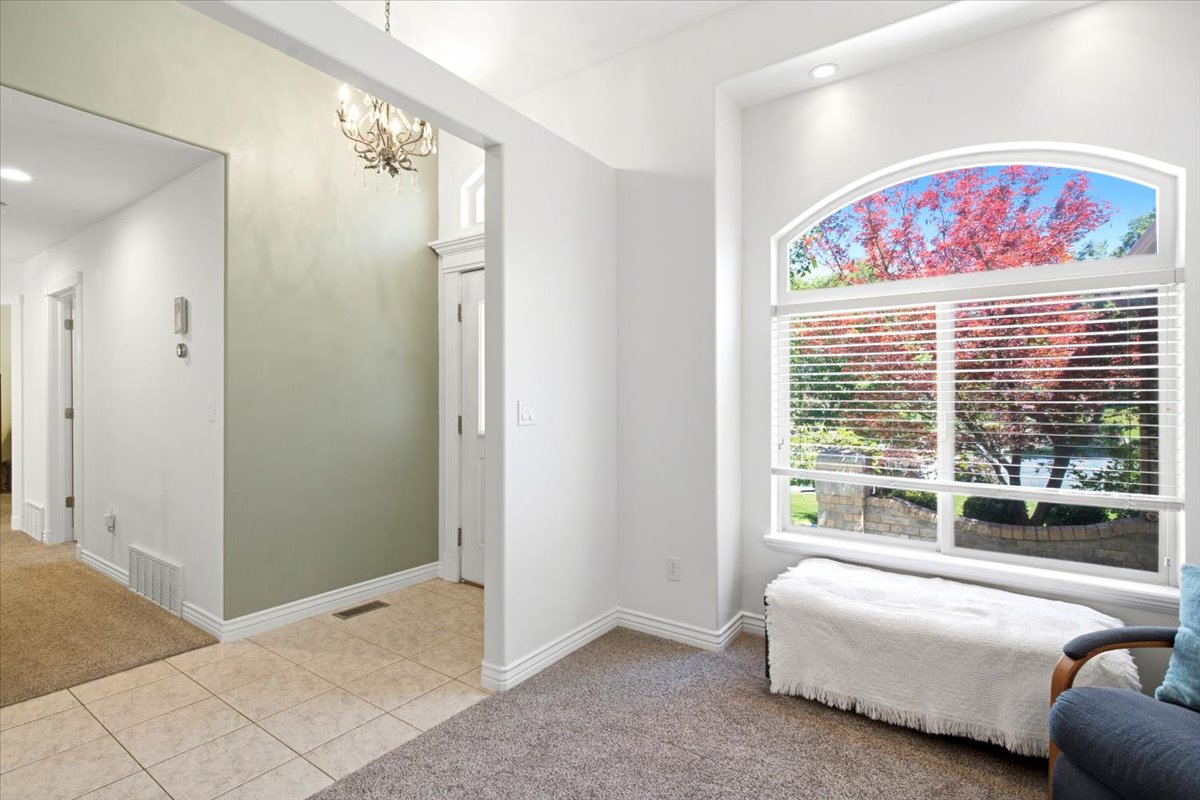 Arch-top picture window with integrated blinds, recessed ceiling lighting, a foyer with tile flooring, a built-in light fixture, and a white paneled entry door
