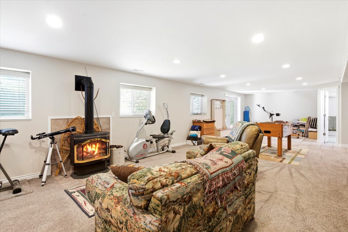 Spacious lower-level area featuring a wood-burning stove with a tiled surround