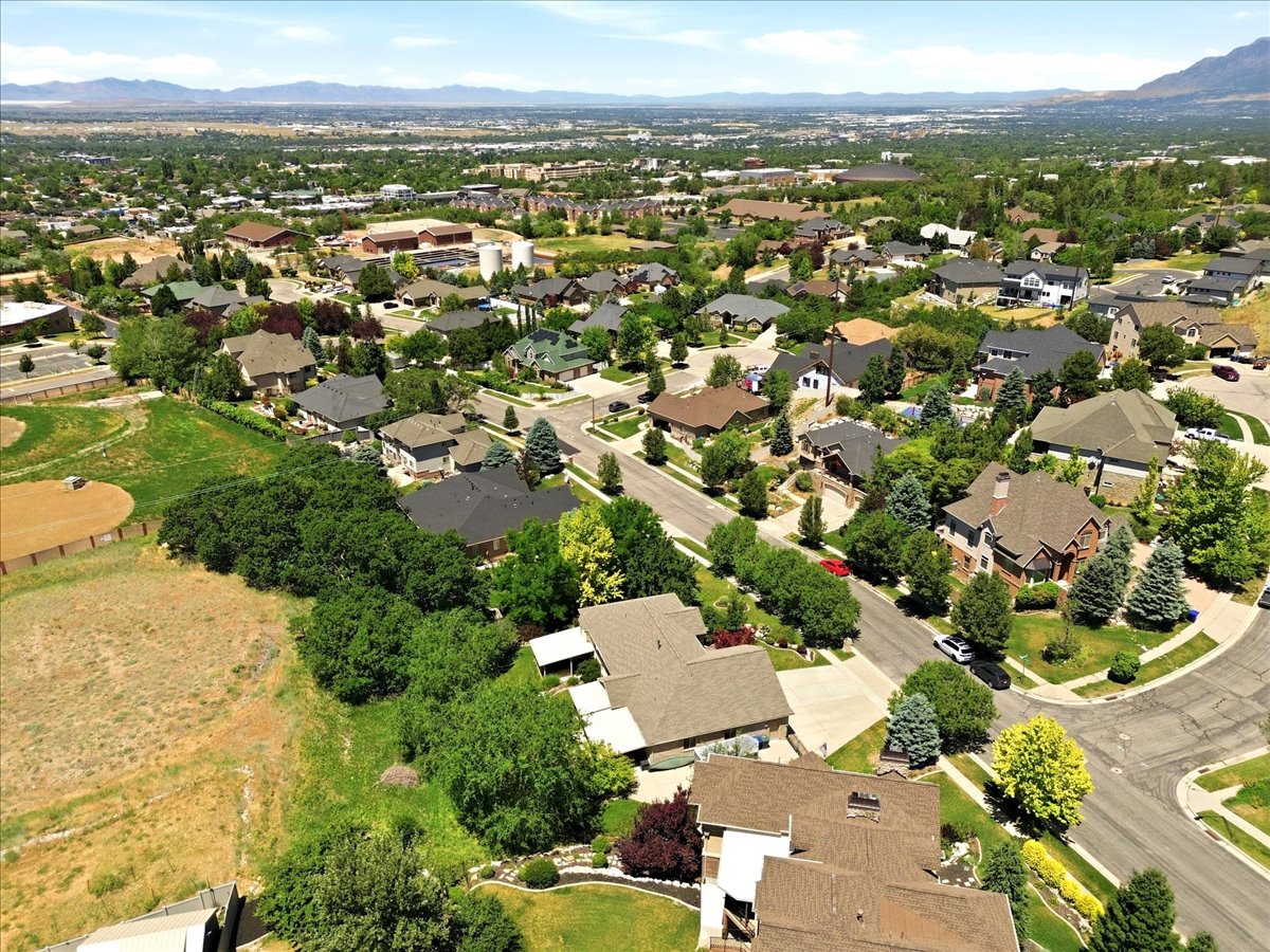 Expansive residential area featuring a variety of architectural styles, mature trees, paved streets, and mountain terrain in the distance
