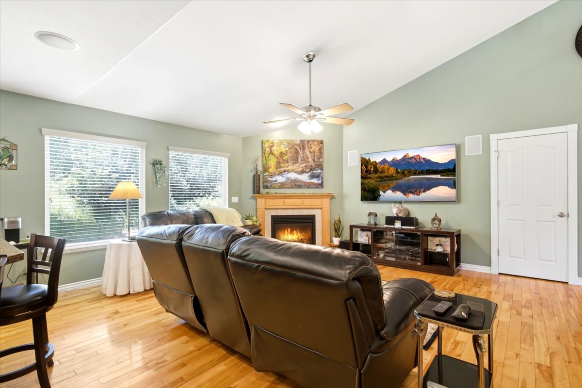 Living area featuring wood-finish flooring, vaulted ceilings, and a corner fireplace with a wood mantle