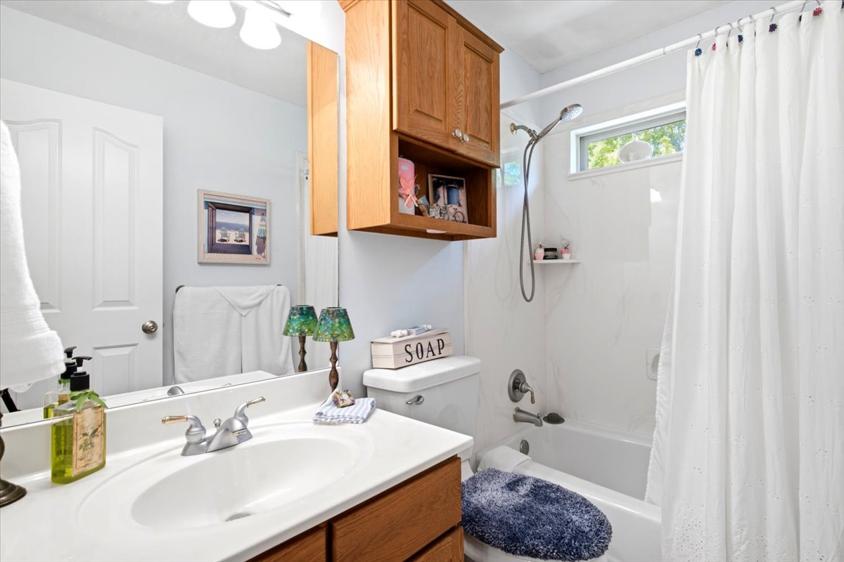 Bathroom featuring a vanity with a white countertop and integrated sink, chrome faucet, and wood-finish cabinetry