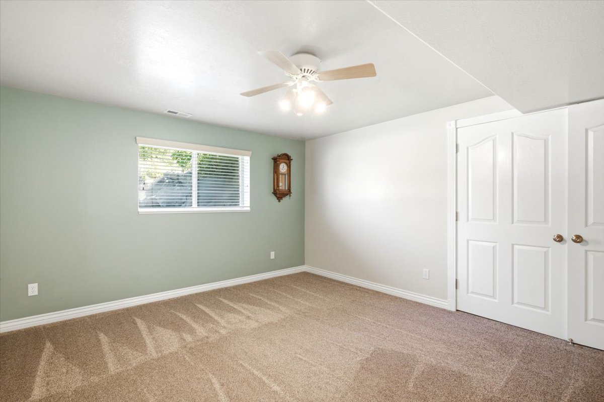 Carpeted room with a ceiling fan light fixture, white trim, and a window with blinds
