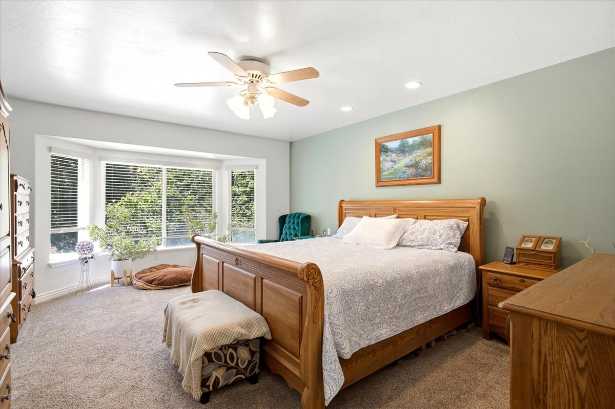 Carpeted bedroom featuring a bay window, recessed lighting, ceiling fan, and painted walls
