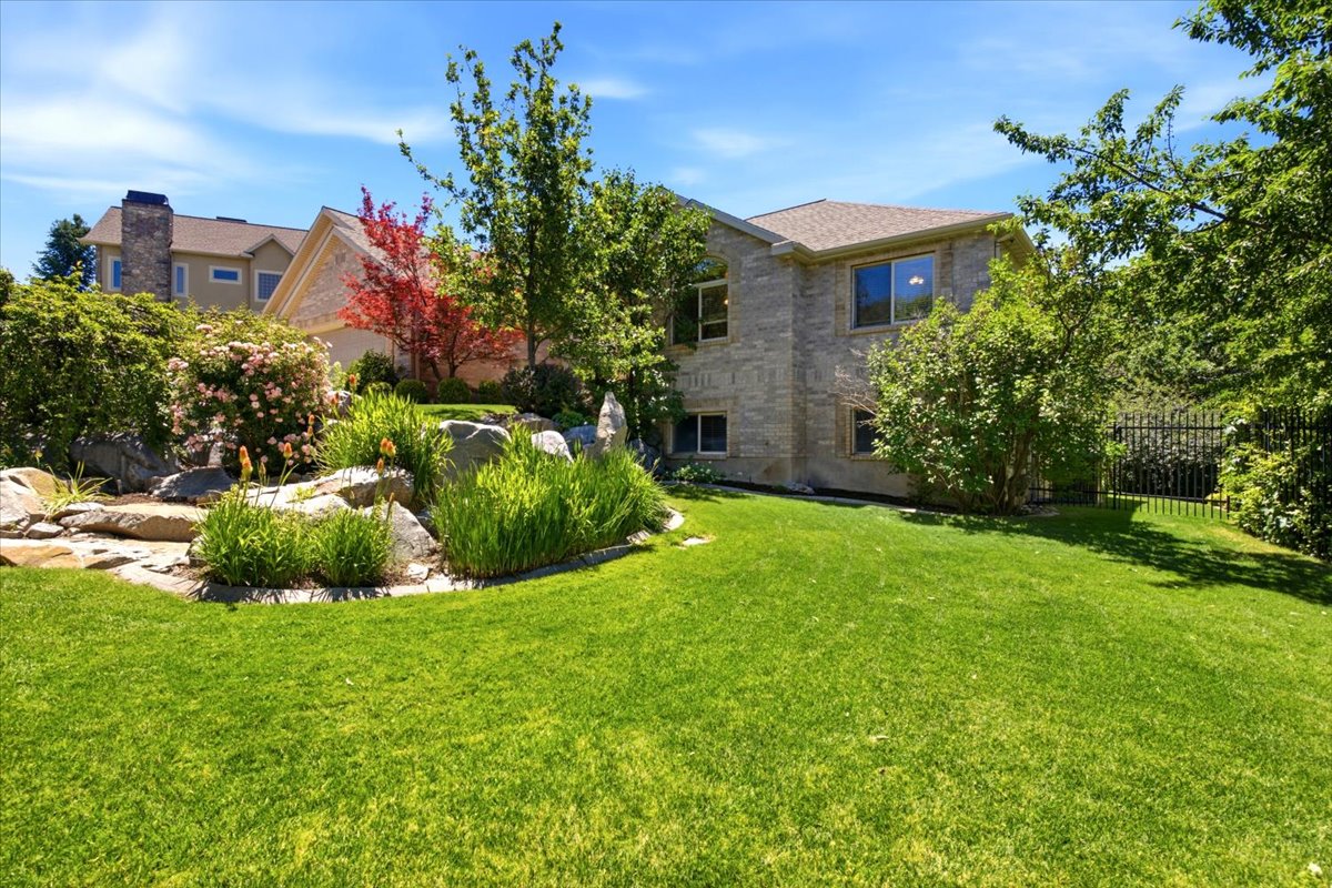 Expansive green lawn with mature trees and a rock garden featuring various plantings