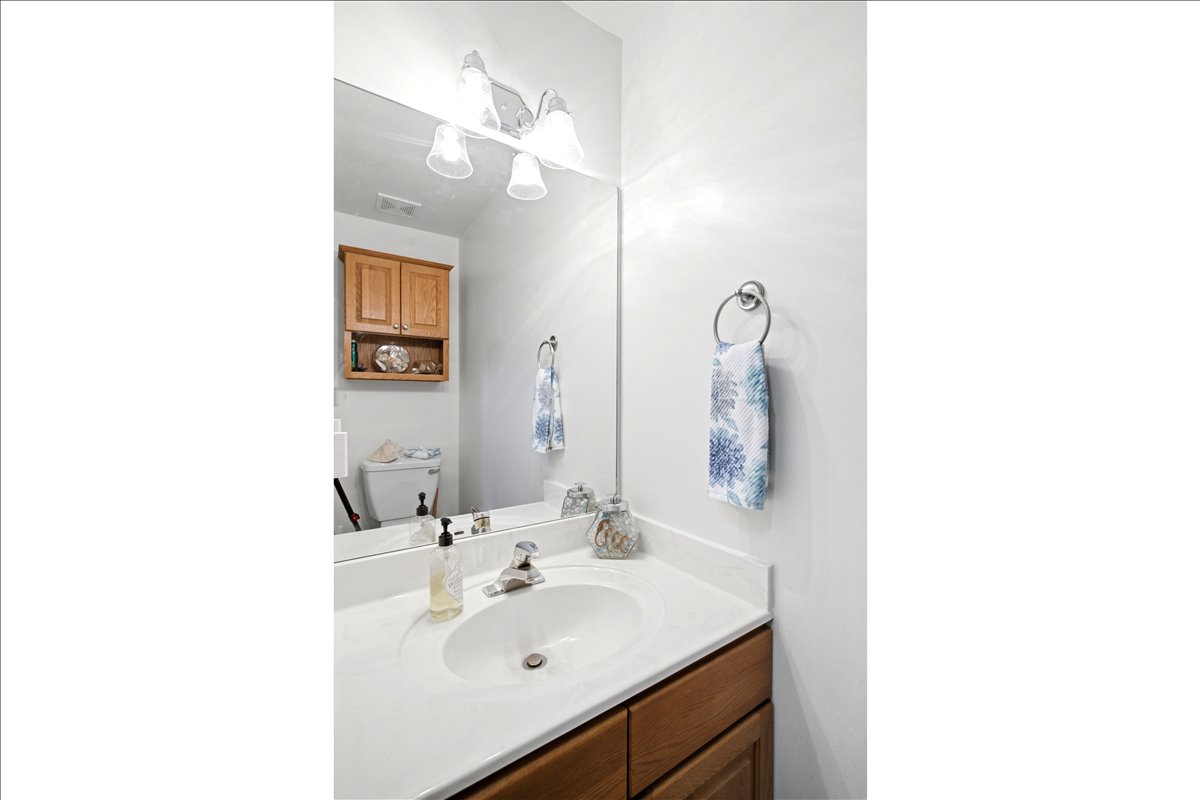 Bathroom vanity featuring a white solid surface countertop, an integrated sink, and a chrome-finish faucet