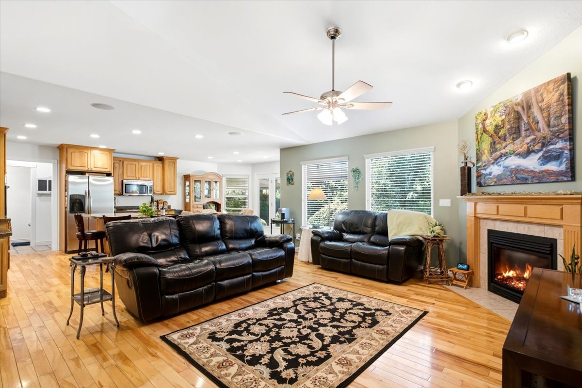 Open-concept living space featuring hardwood flooring and a gas fireplace with a wood mantle