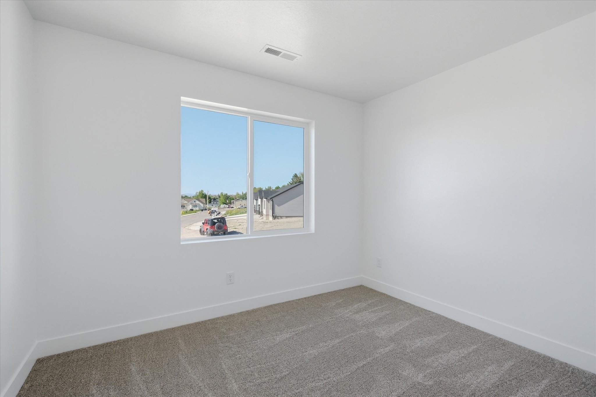 Bright room featuring a large window, neutral carpeting, white walls, and white trim
