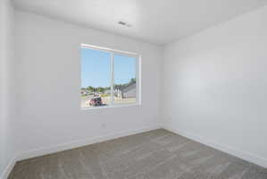 Bright room featuring a large window, neutral carpeting, white walls, and white trim
