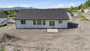 Newly constructed residence featuring white siding, a dark shingle roof, and a concrete patio