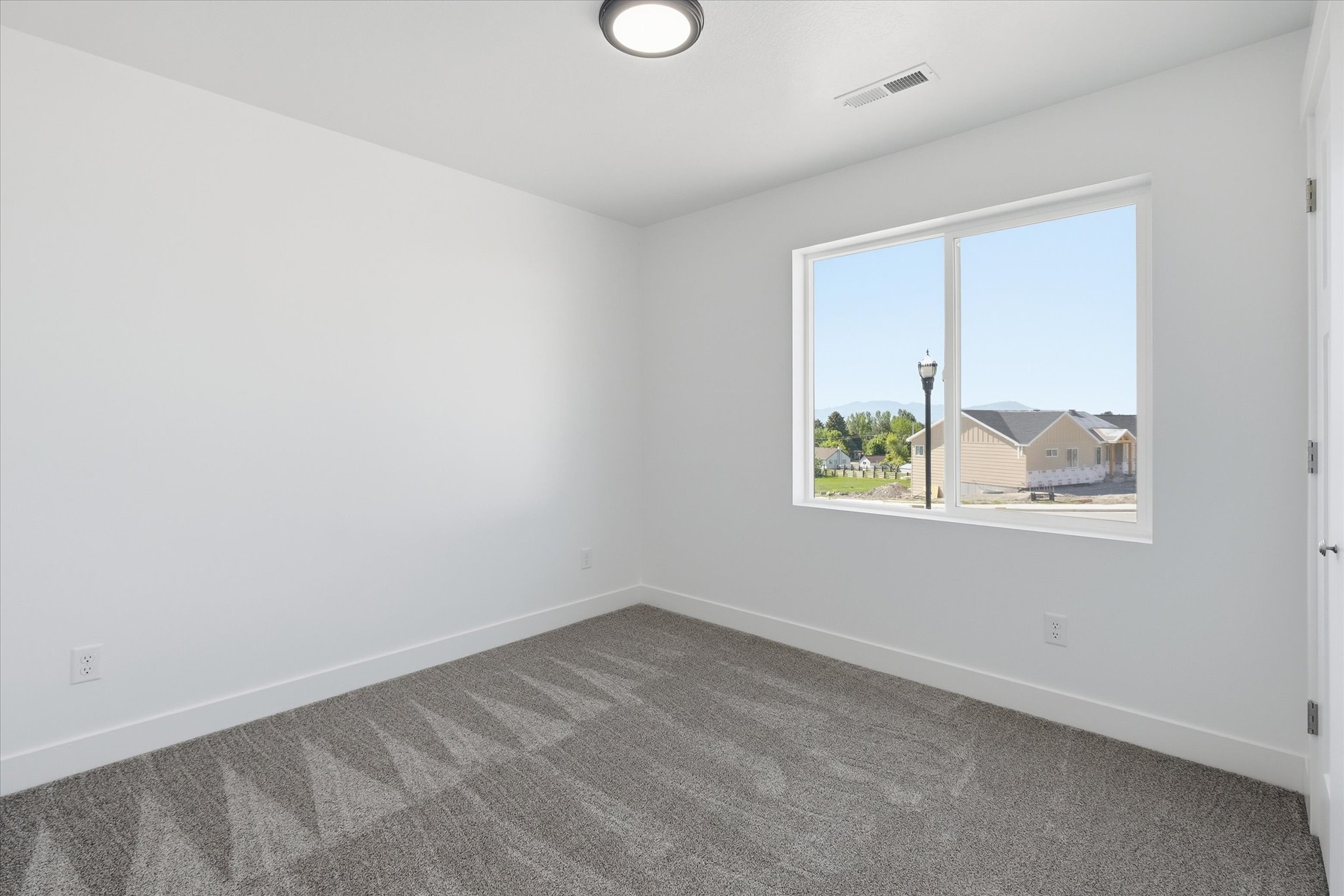 Neutral color palette featuring a large window, recessed lighting, white trim, and patterned carpet