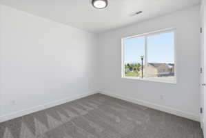Neutral color palette featuring a large window, recessed lighting, white trim, and patterned carpet