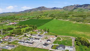 Expansive rural landscape featuring a cluster of residential properties, verdant fields, and distant mountains