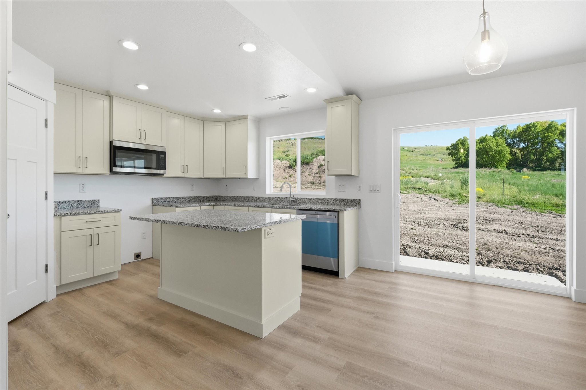 Spacious kitchen with wood-finish flooring, light-toned cabinetry, and granite countertops
