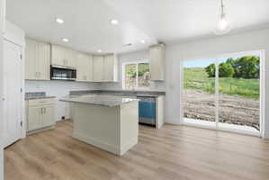 Spacious kitchen with wood-finish flooring, light-toned cabinetry, and granite countertops