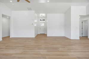 Expansive open-concept living space featuring wood-finish flooring, recessed lighting, and a neutral white color palette