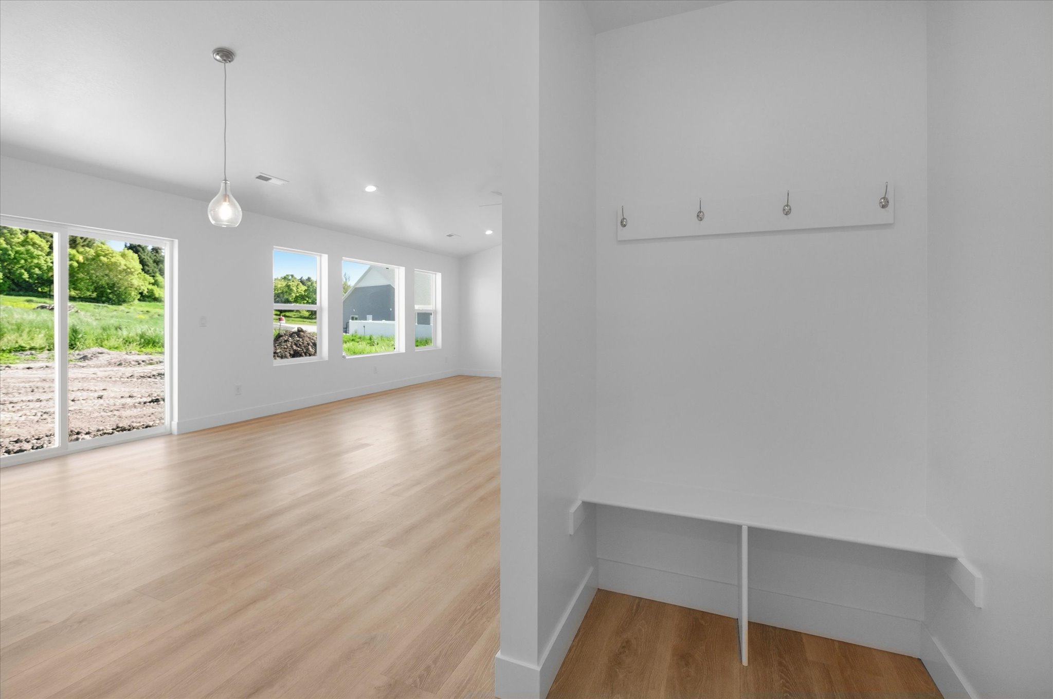 Entryway featuring an integrated bench with storage, wall-mounted hooks, and wood-finish flooring throughout