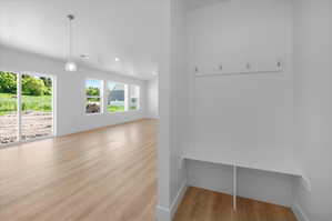 Entryway featuring an integrated bench with storage, wall-mounted hooks, and wood-finish flooring throughout