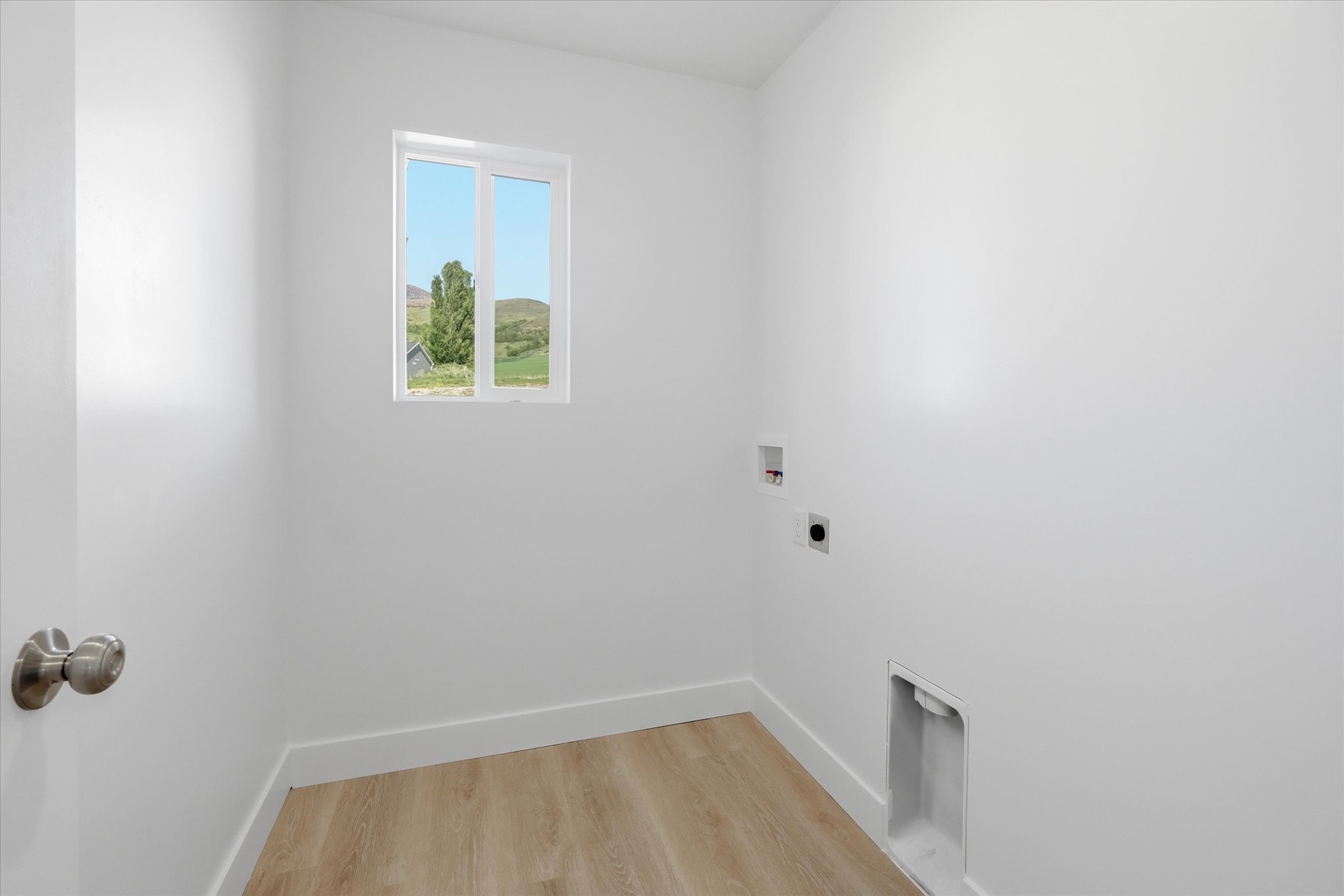 Bright interior space featuring wood-finish flooring, white baseboards, and a window
