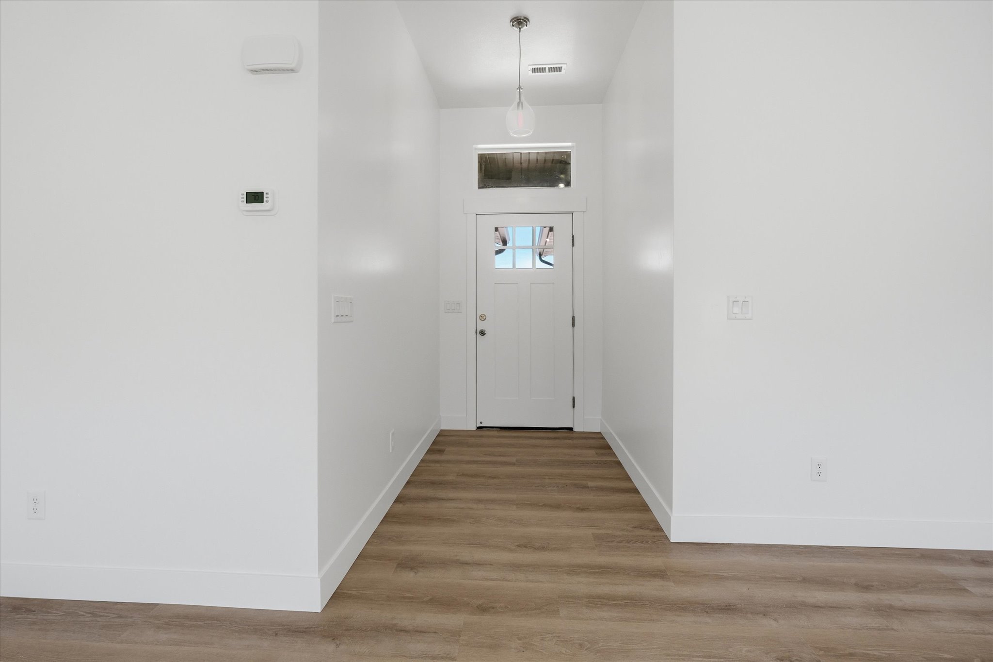 Entryway featuring wood-finish flooring, white walls, and a white paneled door with glass inserts
