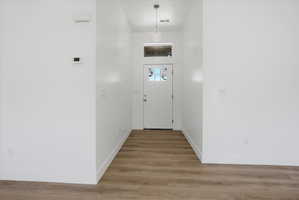 Entryway featuring wood-finish flooring, white walls, and a white paneled door with glass inserts