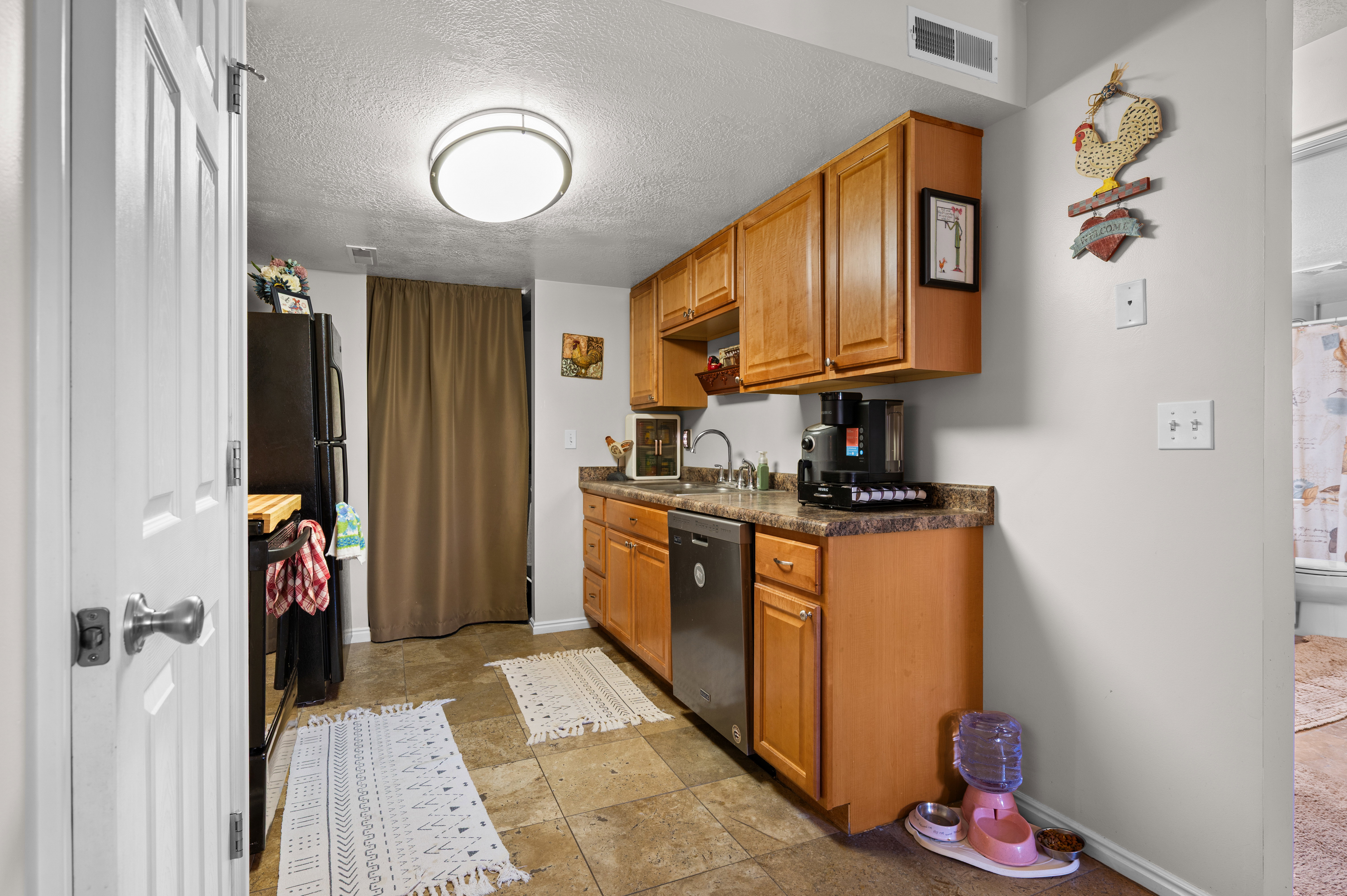 Kitchen featuring wood cabinetry, laminate countertops, stainless steel sink, and integrated dishwasher
