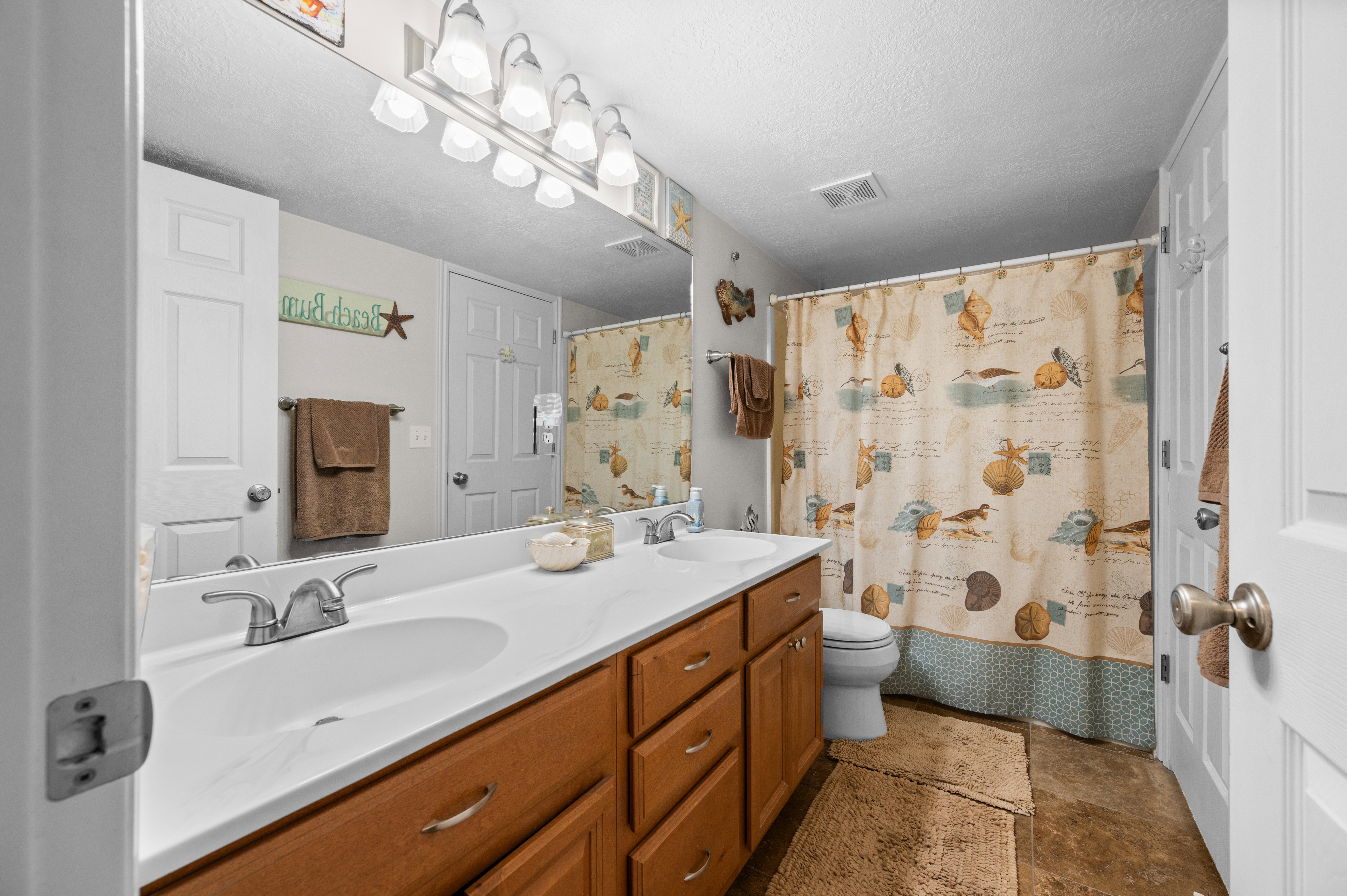 Double vanity with integrated white sinks, chrome faucets, and wood-finish cabinetry