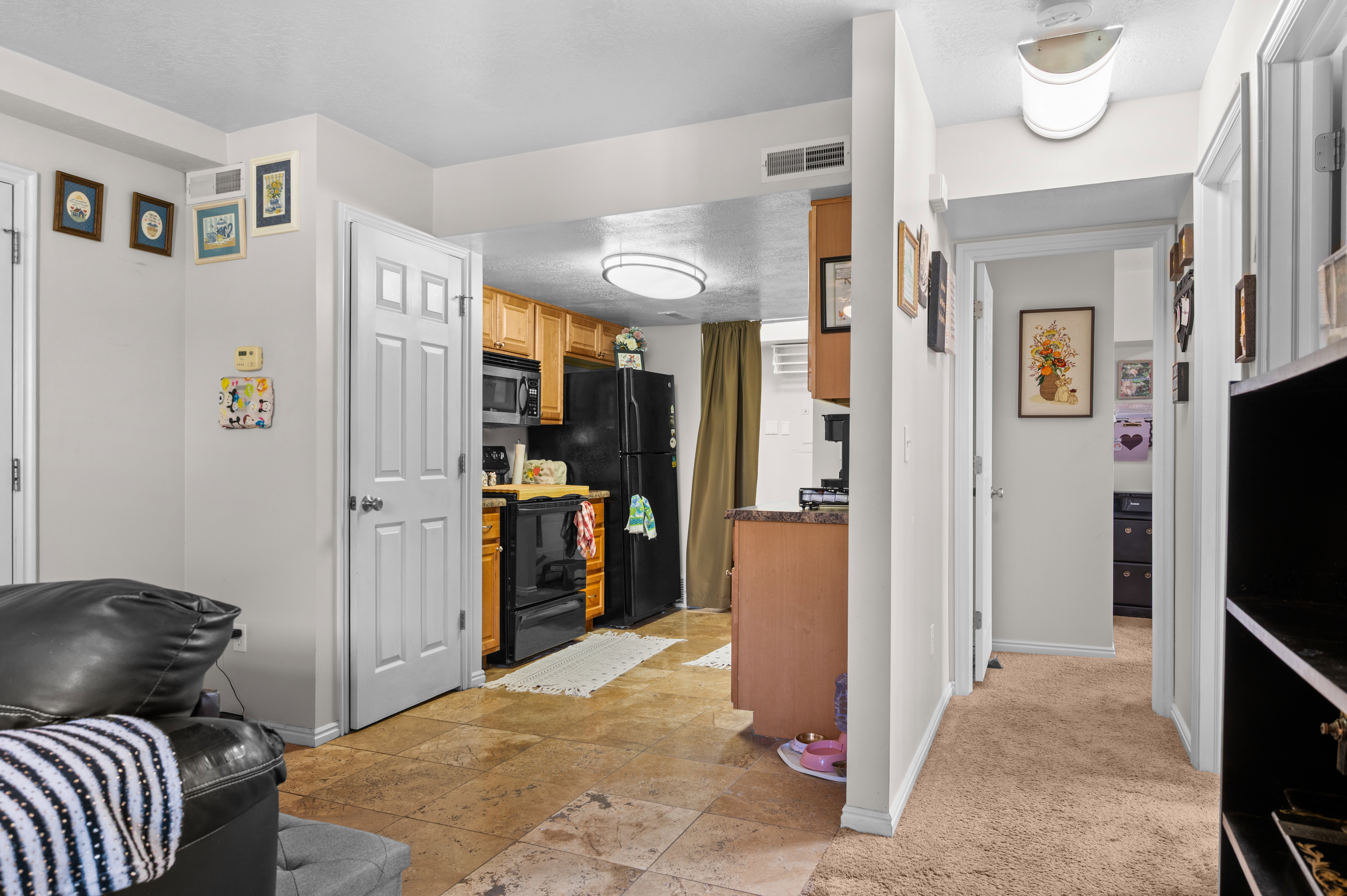 Kitchen featuring wood cabinetry, black appliances, a built-in microwave, and stone-finish flooring