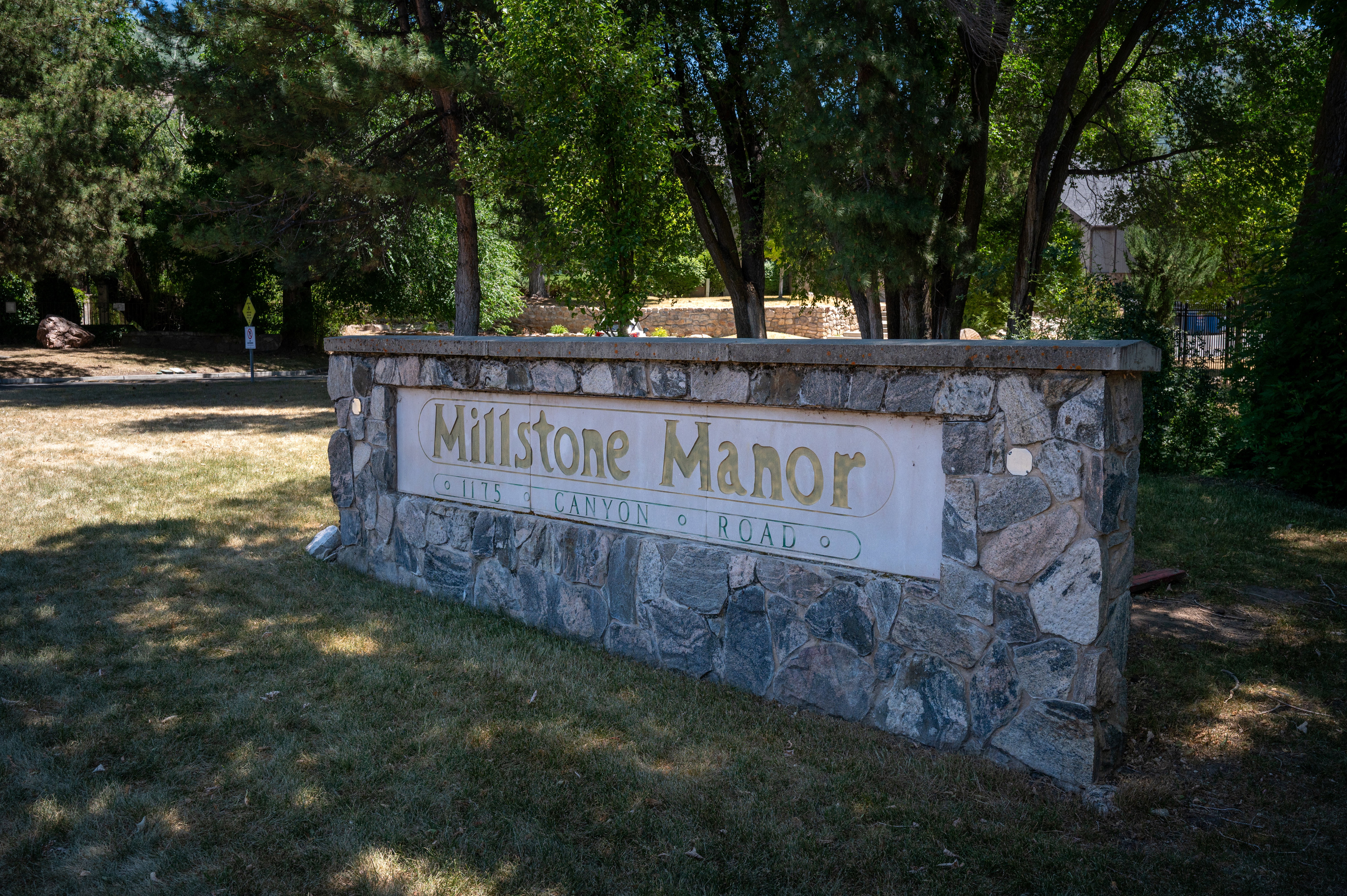 Stone monument signage featuring dimensional lettering for "Millstone Manor" and a street address