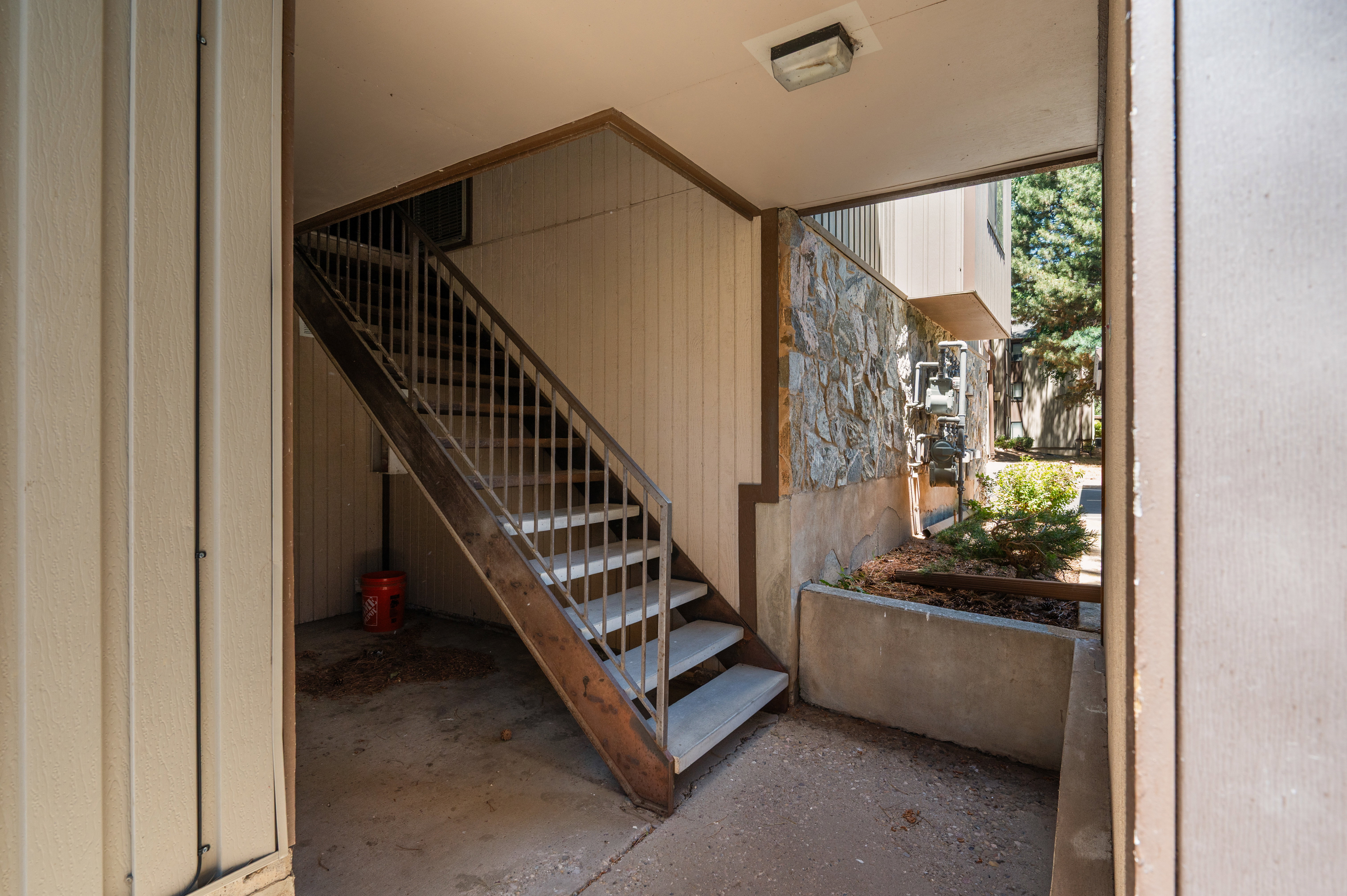 Exterior staircase with metal railings and concrete treads, set against a backdrop of panel siding and a stone accent wall