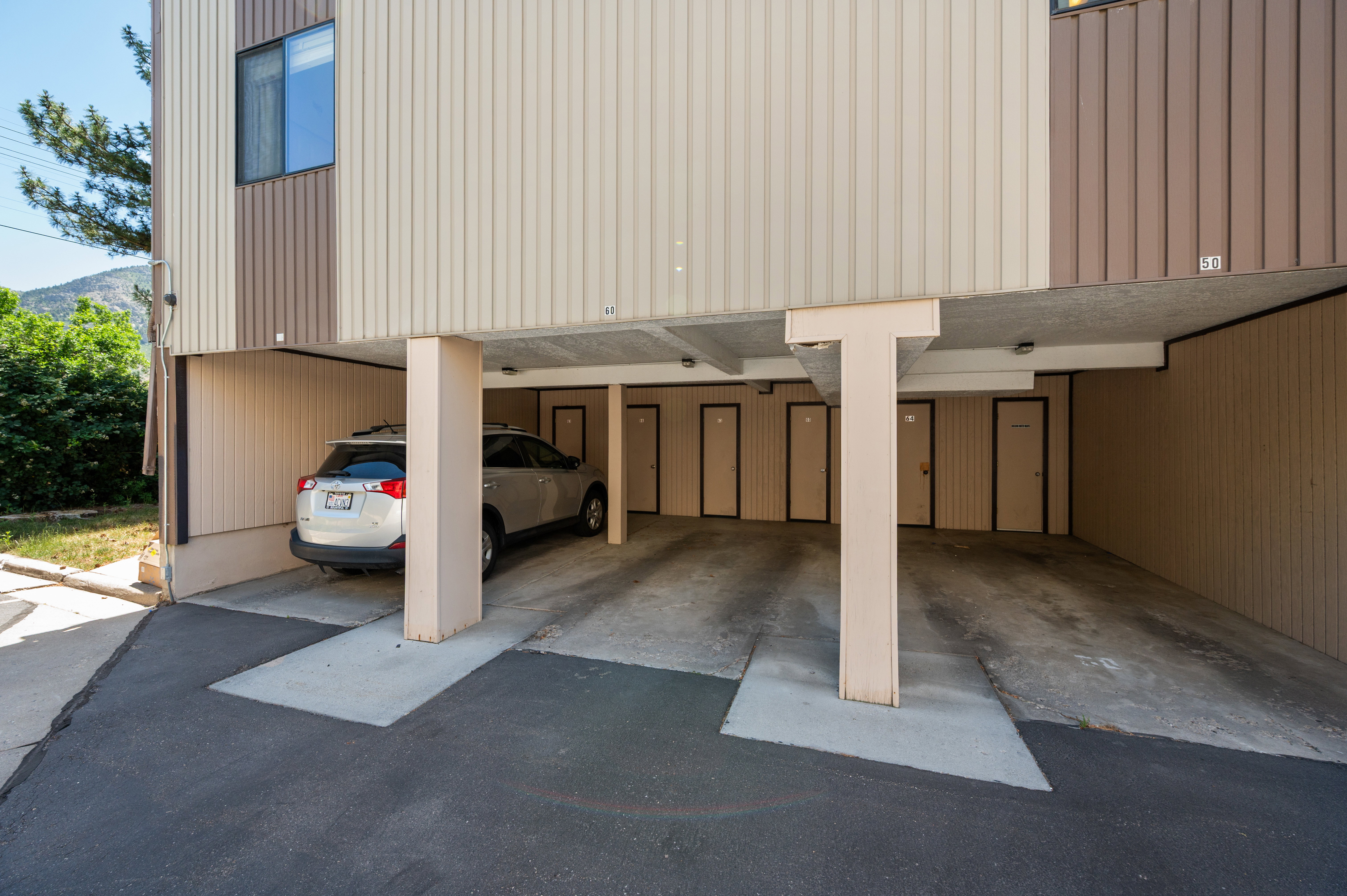 Covered parking area with concrete flooring, featuring multiple storage doors