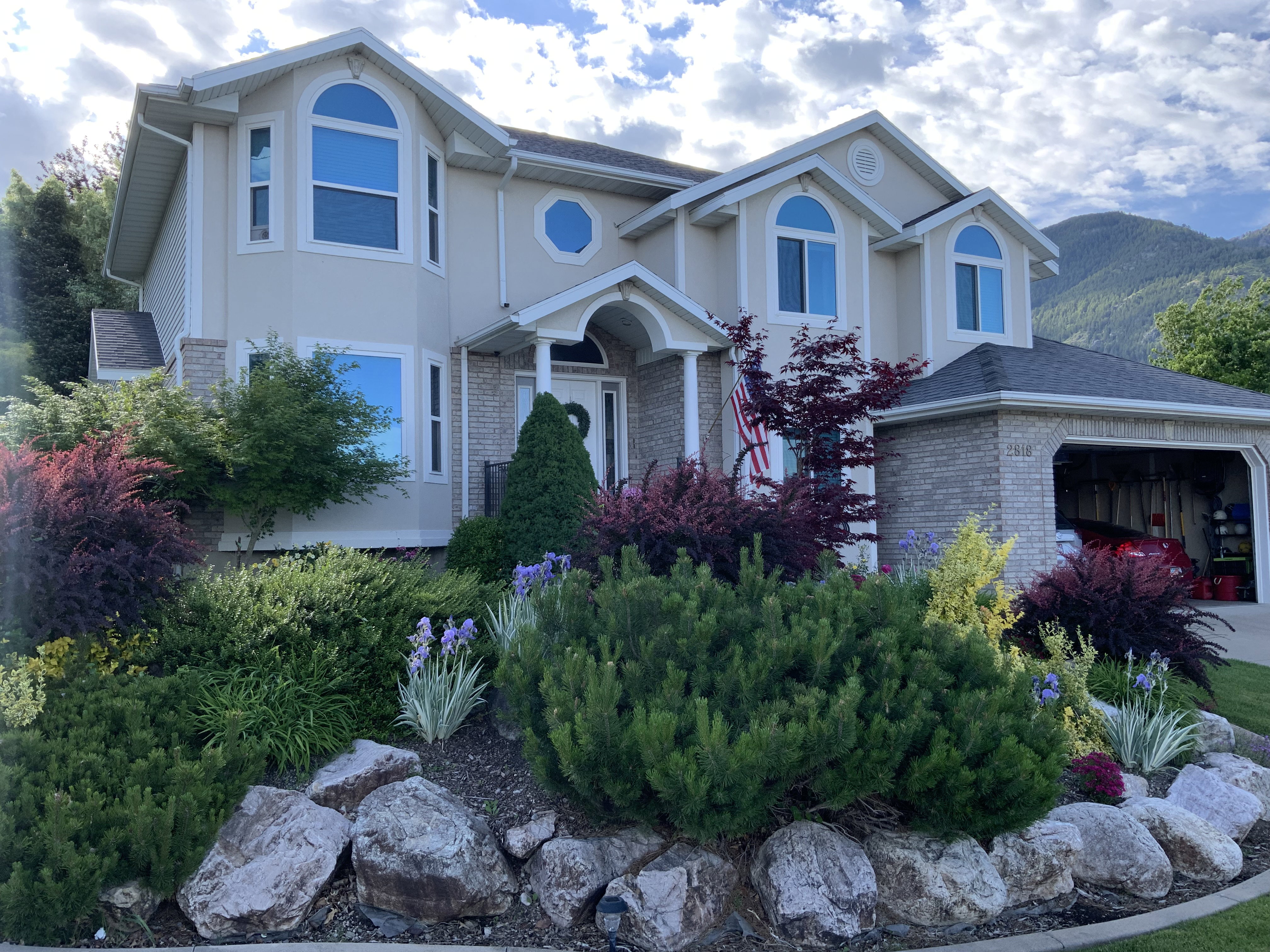Contemporary stucco exterior with brick accents, featuring an arched entry and a two-car garage