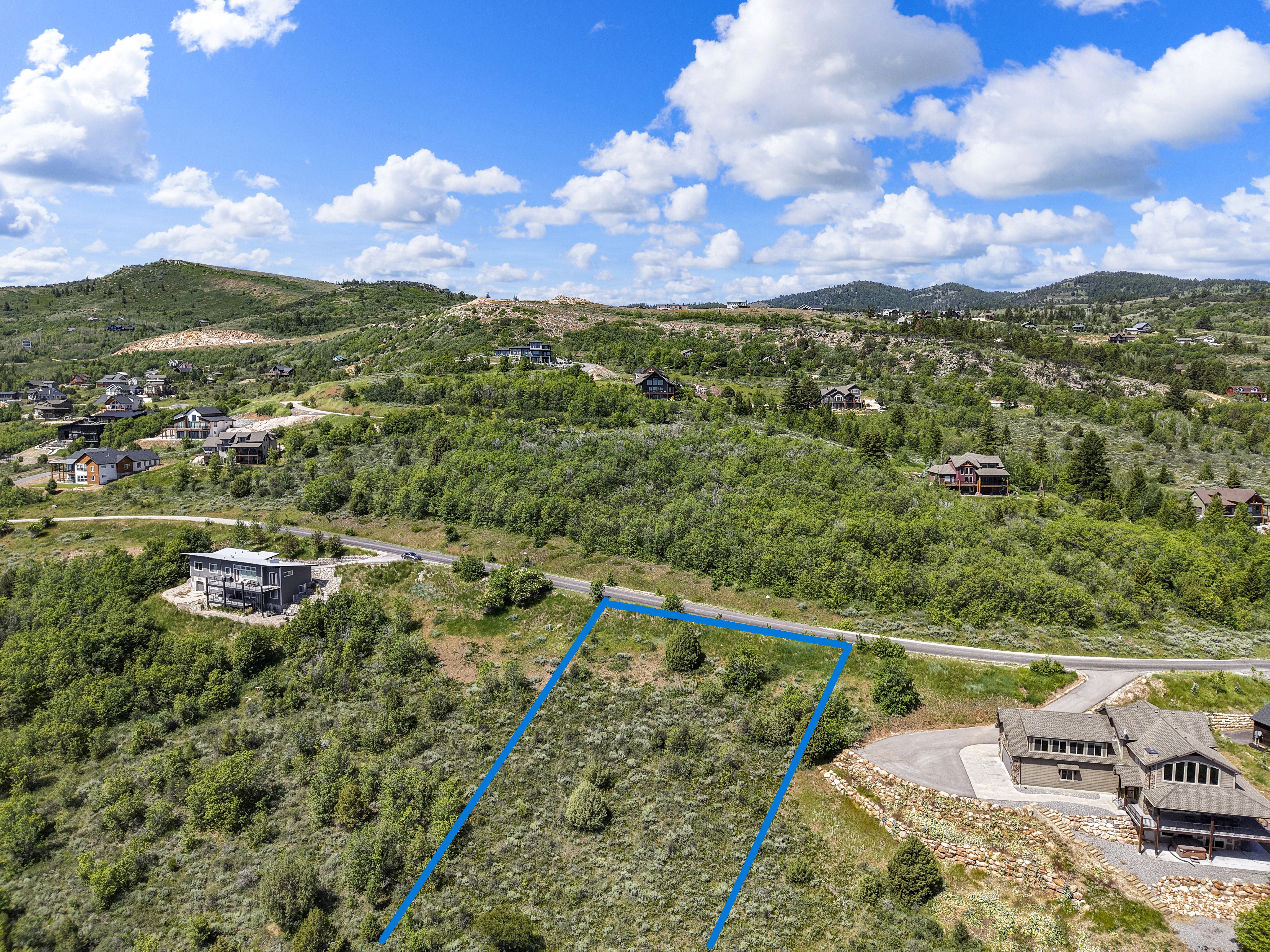 Expansive, undeveloped land parcel featuring natural shrubbery and surrounding mountainous terrain