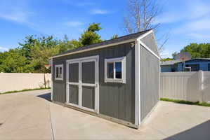 Detached storage shed with a dark gray exterior, white trim, and a black shingle roof