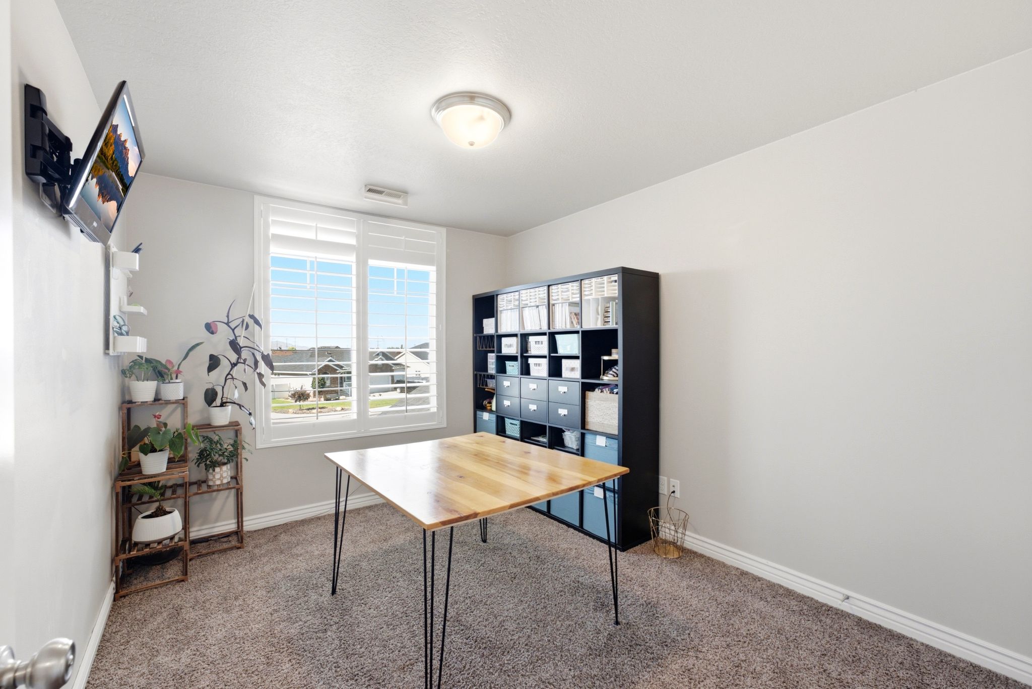 Room featuring a large window with white louvered shutters, light gray wall paint, and gray carpet