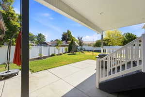 Covered patio featuring a concrete surface, white railings, and a direct entrance to the expansive grass lawn