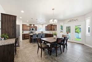 Spacious kitchen and dining area featuring dark wood cabinetry, stainless steel appliances, a large center island with seating, and durable tile flooring
