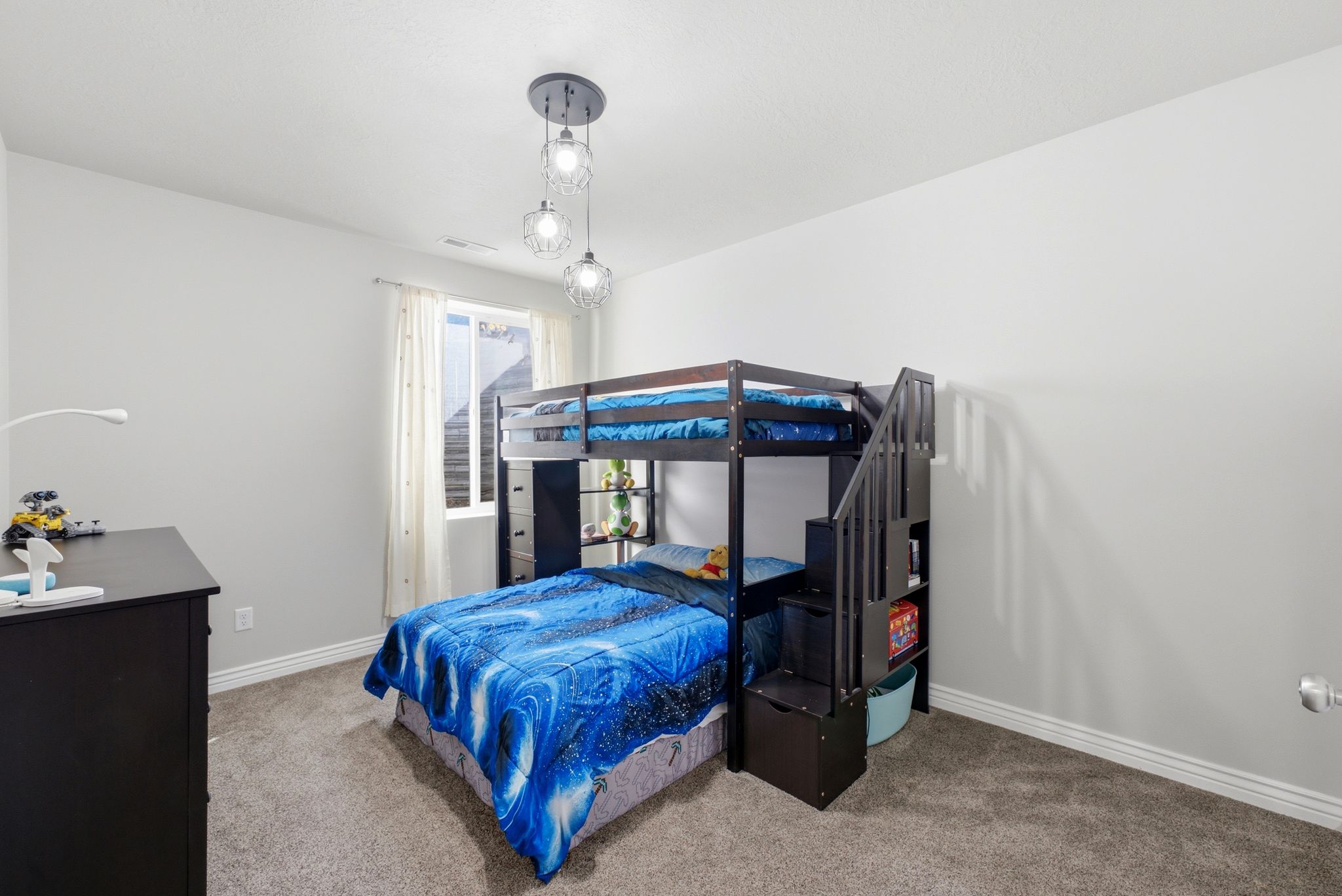 Carpeted room featuring a window with white blinds and curtains, a multi-light ceiling fixture, and light gray wall paint with white trim