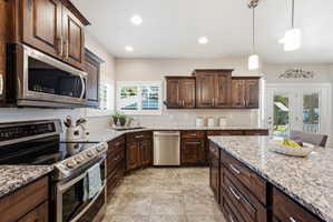 Kitchen featuring wood cabinetry, stainless steel appliances, and granite countertops