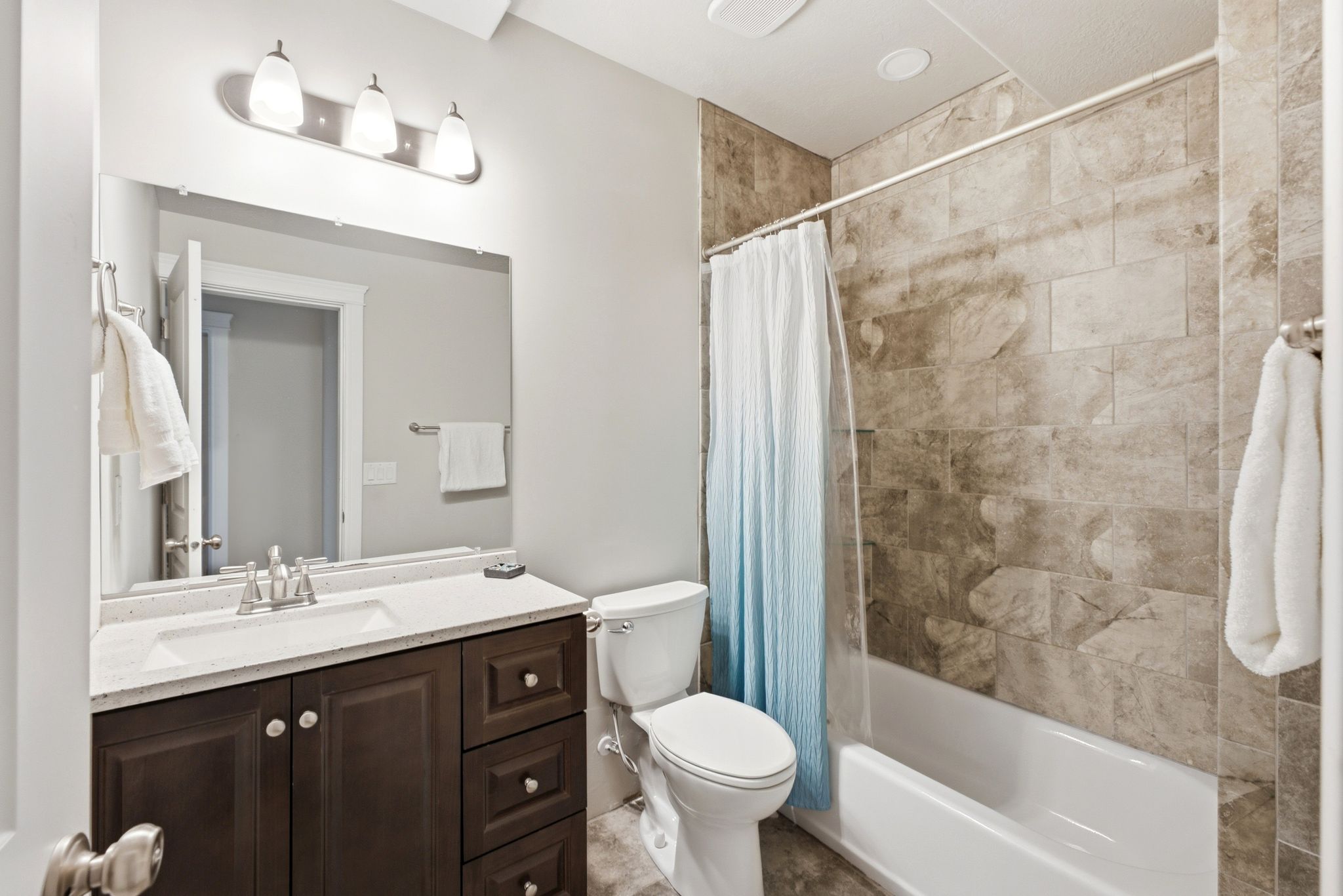 Bathroom featuring a vanity with dark wood-finish cabinetry, a white countertop with an integrated sink, and a chrome faucet