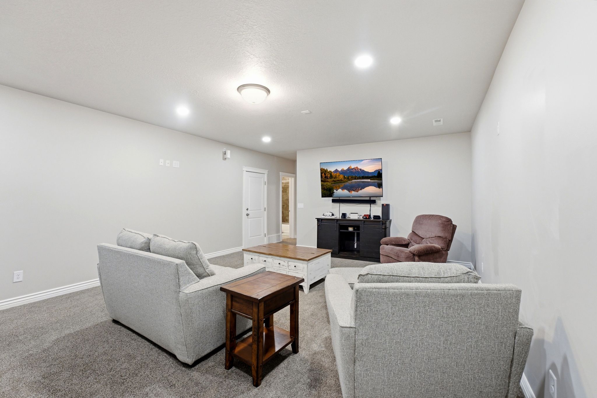 Living area featuring plush gray carpeting, recessed lighting, and a built-in entertainment console