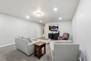 Living area featuring plush gray carpeting, recessed lighting, and a built-in entertainment console