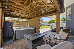 Covered patio featuring a hot tub, string lighting, and a slatted wood privacy screen